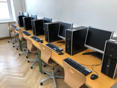 Ein IT Saal der AHS-Rahlgasse. Zu sehen sind mehrere Computer, die an einer Wand in einer Reihe stehen.