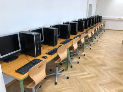 Ein IT Saal der AHS-Rahlgasse. Zu sehen sind mehrere Computer, die an einer Wand in einer Reihe stehen.